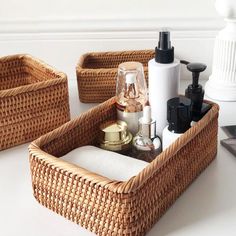 three wicker baskets with soap, lotion and other items in them on a table