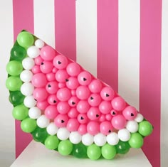 a watermelon shaped balloon sculpture with green, white and pink balloons on it