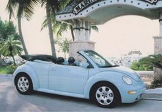 a light blue convertible car parked in front of a building with the name marina drive written on it