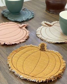 four coasters with different designs on them sitting on a table next to coffee cups