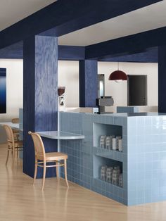 an empty kitchen with blue tiles and wooden chairs in front of the counter top area