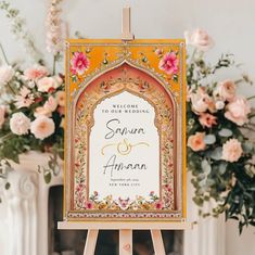 an orange and yellow wedding sign with pink flowers in the background on top of a easel