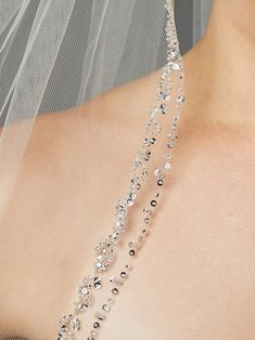 the back of a bride's wedding dress with a veil over her shoulder and beads on it