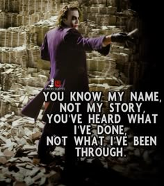 the joker is holding his hand out in front of stacks of bricks and pointing at something