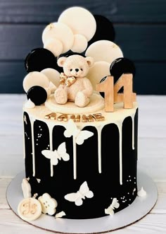 a black and white birthday cake with a teddy bear sitting on top of the cake