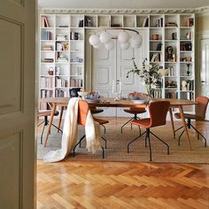 a dining room table and chairs with bookshelves in the background