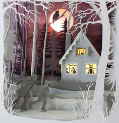 a paper cut out of a house and trees with the moon in the sky behind it