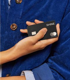 a person holding a black credit card in their left hand with the word shine on it