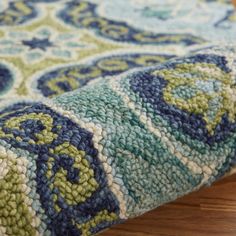 a close up view of a blue and green rug on a wooden floor with wood floors