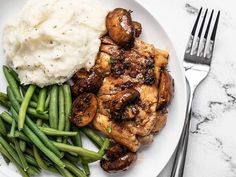 a white plate topped with meat, mashed potatoes and green beans