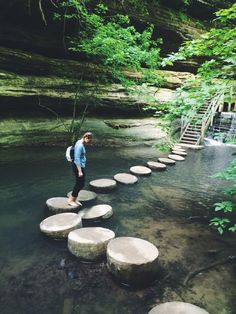 a man is standing on stepping stones in the water