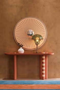 a table with a lamp on top of it in front of a wall mounted disc