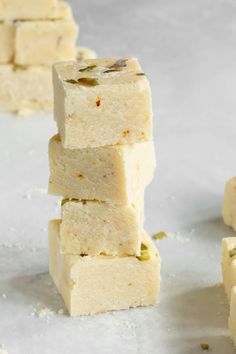 several pieces of white fudge stacked on top of each other with seeds scattered around them