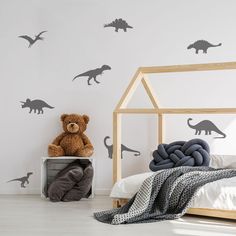 a child's bedroom with dinosaur decals on the wall and a teddy bear