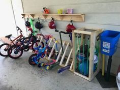 a garage with several different types of bikes and toys hanging on the side of it