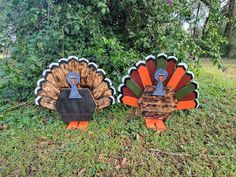 two wooden turkeys sitting in the grass