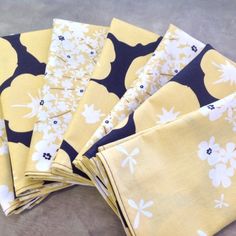 four yellow and black napkins with white flowers on them