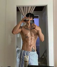 a shirtless man taking a selfie in front of a mirror with his camera