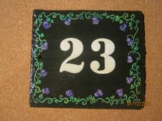 the number twenty three is decorated with purple flowers and green vines on a black background