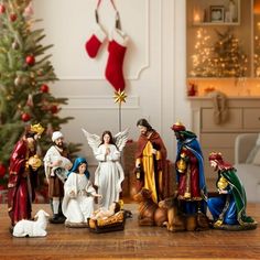 a group of figurines sitting on top of a wooden table next to a christmas tree