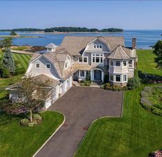 an aerial view of a large house with lots of grass and water in the background