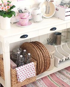 a white table topped with lots of baskets and bottles next to a mirror on top of a wall