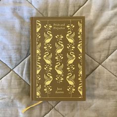 a brown book with yellow birds on it sitting on top of a white quilted bed