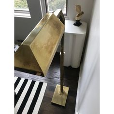 a gold lamp sitting on top of a wooden floor next to a white and black rug