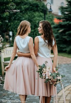 two women standing next to each other wearing dresses and holding bouquets in their hands