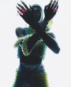 a woman with her hands up in the air, wearing a green and blue dress