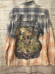 an old shirt hanging on a wall with the image of a skull and two hands painted on it