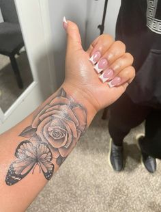 a woman's arm with a rose and butterfly tattoo on the left side of her arm