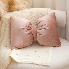 two pink pillows sitting on top of a white chair next to a stuffed teddy bear