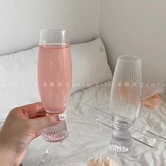 a person holding a wine glass in front of a bed