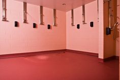 an empty room with pink walls and red flooring in front of the door to another room