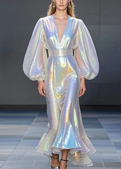 a model walks the runway in an iridescent gown with long sleeves and high slits