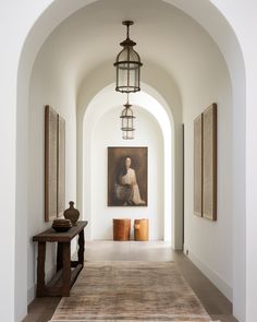 an archway leading to a large painting in the middle of a room with two vases on either side