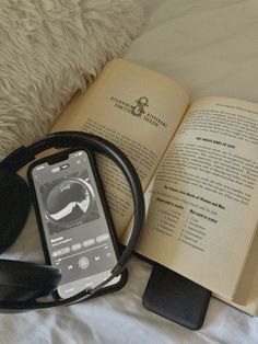 an open book and headphones on a bed