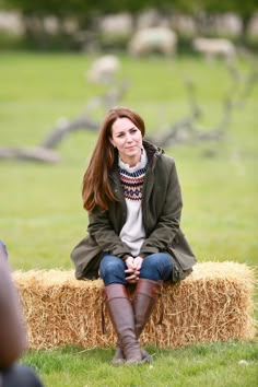 a woman sitting on top of a hay bale