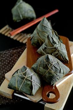 some food is sitting on a wooden tray with chopsticks in front of it