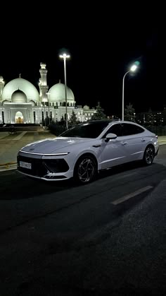 a white car parked in front of a building at night