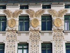 the front of a building with gold decorations on it's sides and two faces