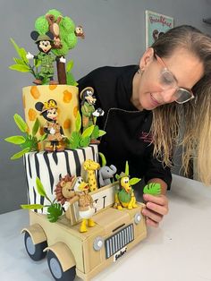 a woman is looking at a cake made to look like an army vehicle with cartoon characters on it