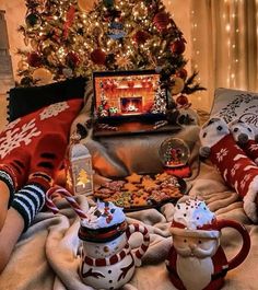 two teapots are sitting on a blanket next to a christmas tree and other decorations