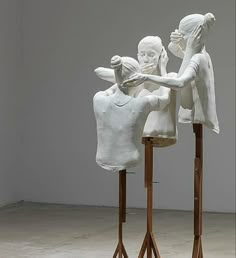 three white sculptures sitting on top of wooden stands