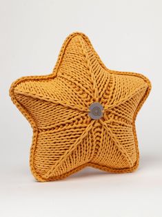 a yellow knitted star ornament with a button on the center, sitting against a white background