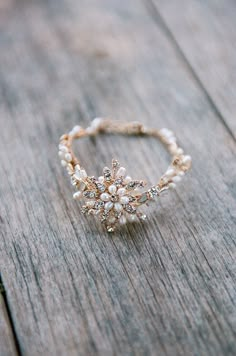 a close up of a ring on a wooden surface with beads and pearls around it