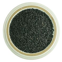 a white and gold bowl filled with black seeds