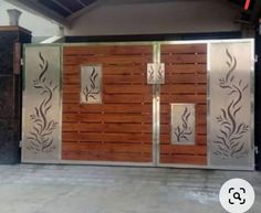 a large metal gate with wooden panels and decorative designs on the sides, in front of a building