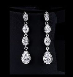 a pair of diamond earrings on a mannequin neckline in front of a black background